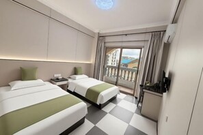 Habitación de hotel con dos camas, un balcón y una mesa de recepción.