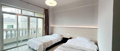 Una habitación de hotel moderna con dos camas, ventanas amplias y un balcón.