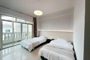 Una habitación de hotel moderna con dos camas, ventanas amplias y un balcón.