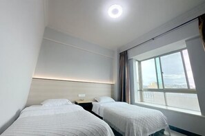 Una habitación de hotel con dos camas, un ventanal grande y una lámpara en el techo.