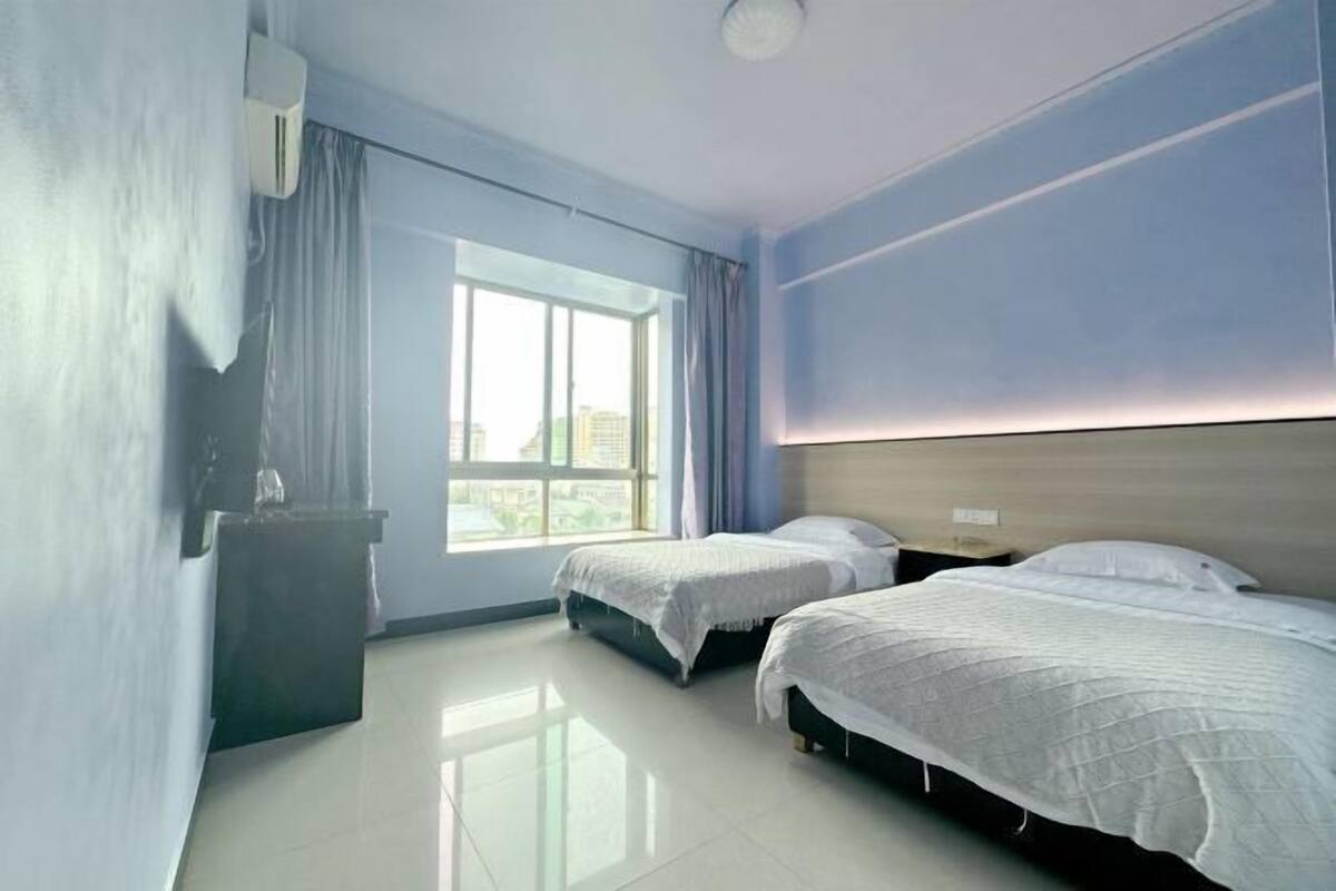 Ett hotellrum med två sängar, ett fönster och en väggmonterad luftkonditioneringsanläggning.