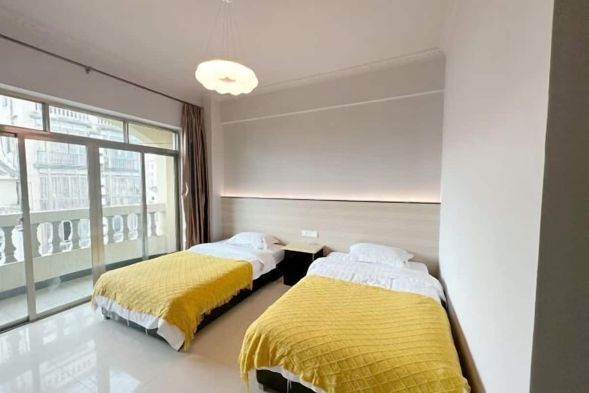 Habitación de hotel con dos camas, un ventanal con vistas a edificios y una lámpara moderna.