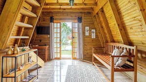 A cozy attic room with wooden walls, a large window, a wooden bench, and a rug. - Chalé 3 Família (Angra dos Reis)