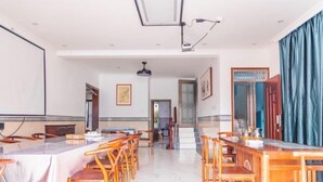A spacious conference room with a long table and chairs, a ceiling light, and a door with a blue curtain. - Caixia Inn (Shenzhen Xiyong Dapeng Branch) (Shenzhen)
