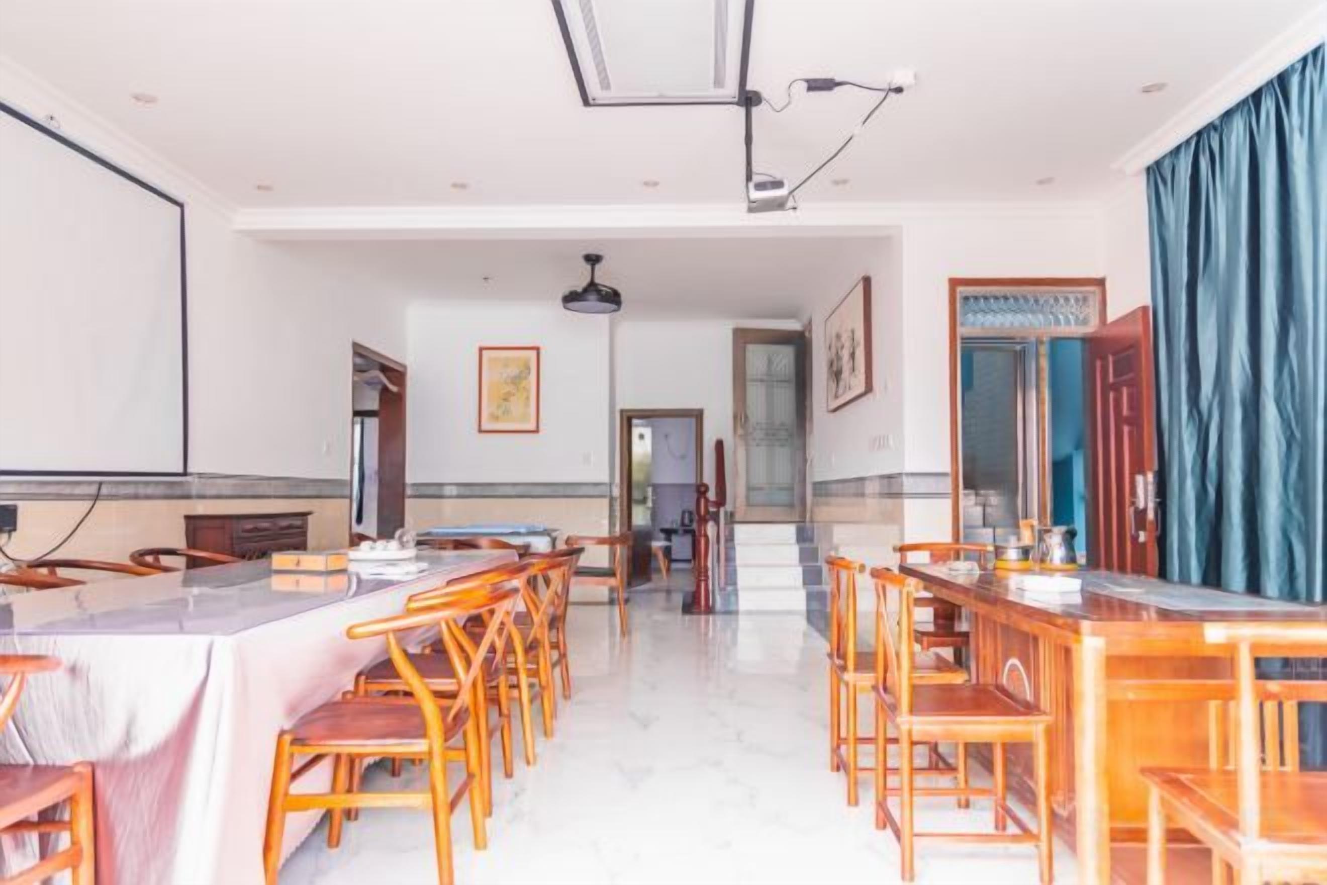 Un comedor de hotel con varias mesas y sillas, una larga barra y vistas al pasillo.