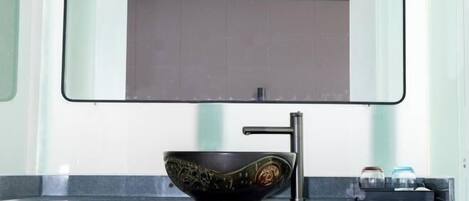 A modern bathroom with a black ceramic sink, a single faucet, and a mirror above it.