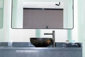 Un bagno moderno con un lavabo in ceramica nera, un rubinetto e uno specchio sopra.