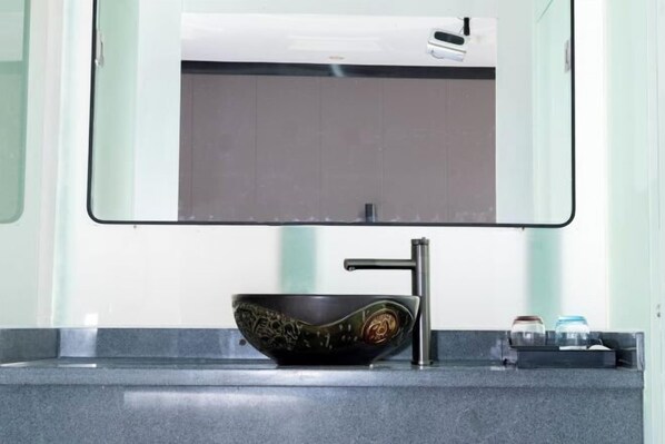 A modern bathroom with a black ceramic sink, a single faucet, and a mirror above it. - Caixia Inn (Shenzhen Xiyong Dapeng Branch) (Shenzhen)