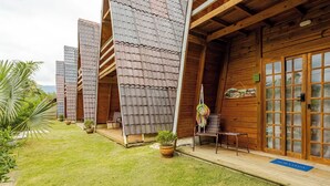 A row of wooden cabins with sloped roofs, each with a small porch and a chair. - Chalé 4 Familia (Angra dos Reis)