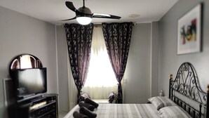 Ein Schlafzimmer mit einem Bett, einem Fernseher und einem Deckenventilator.