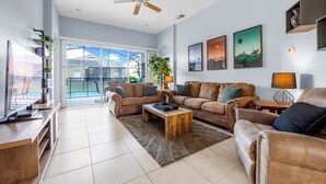 A spacious living room with a large window, a ceiling fan, and a fireplace.