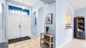 A modern hallway with a double door, a small wooden console table with a plant, and a framed artwork on the wall.