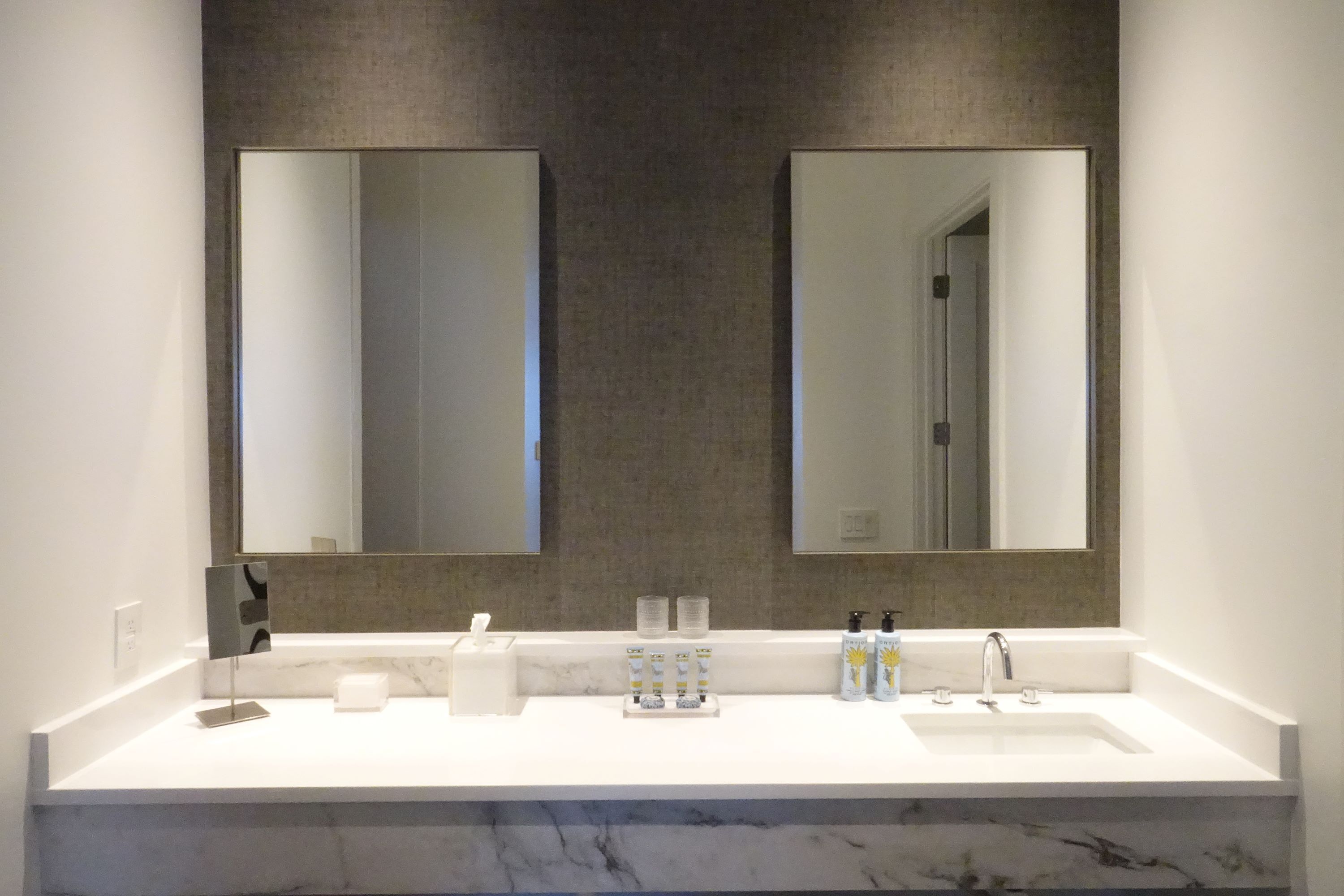 A modern bathroom with a large mirror, two sinks, and a marble countertop.