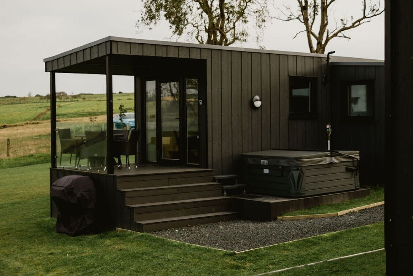 Un bâtiment moderne aux couleurs sombres, doté d’un porche vitré et d’un jacuzzi.