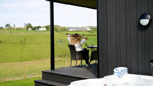 Eine Holzterrasse mit Whirlpool und Sitzgelegenheit im Freien.