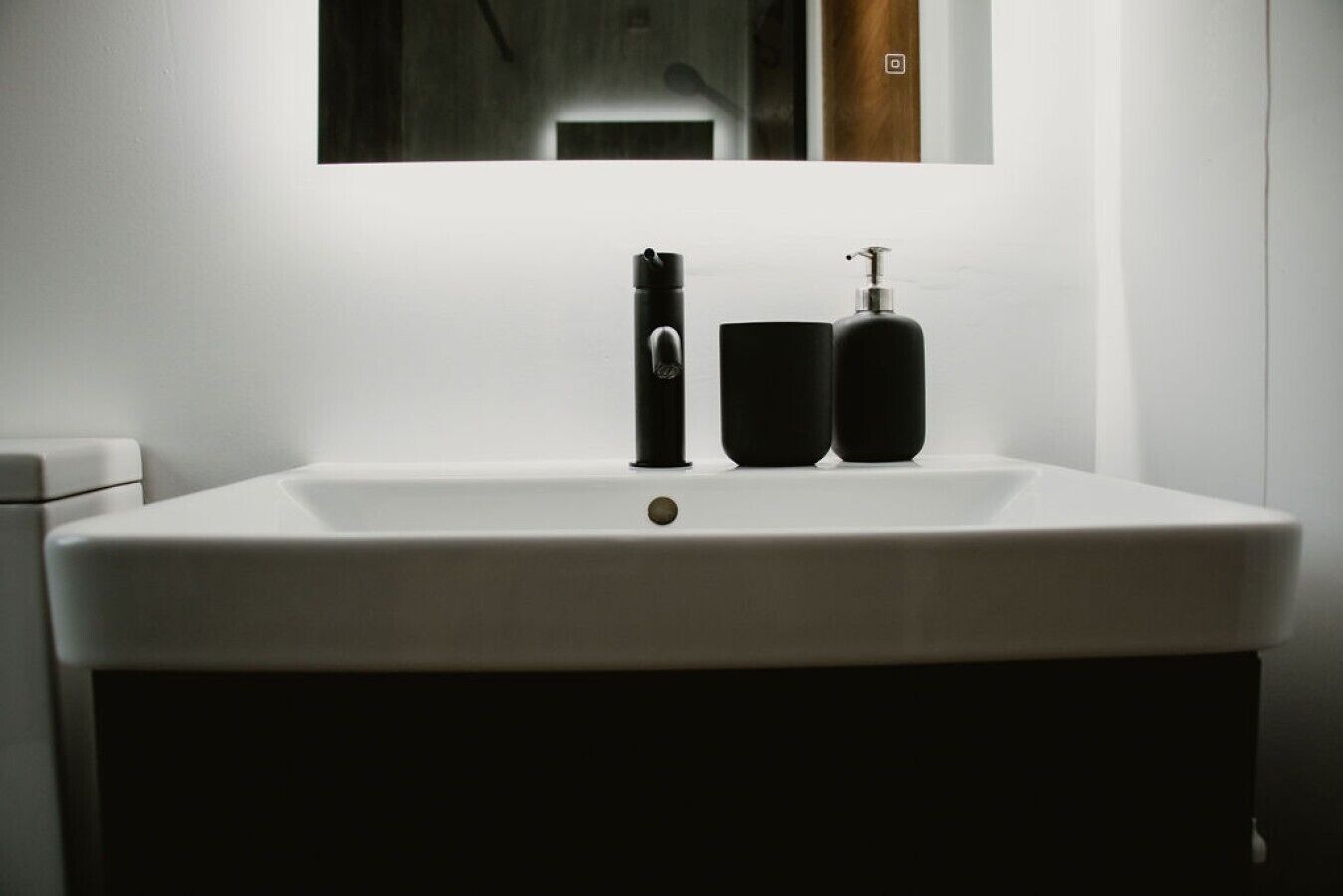 Ein Badezimmer mit einem weißen Waschbecken, einem schwarzen Wasserhahn und zwei schwarzen Seifenspendern.