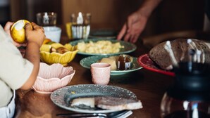 A dining table with various dishes, including bread, cheese, and a bowl of fruit.