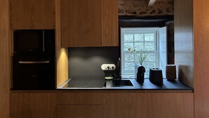 A kitchen with wooden cabinets, a built-in oven, a stove, a sink, and a window with a view of trees.