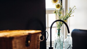 A wicker basket, a glass vase with flowers, and a black metal structure.