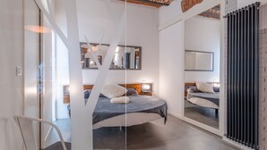 Un dormitorio moderno con una cama grande, un espejo y un radiador.