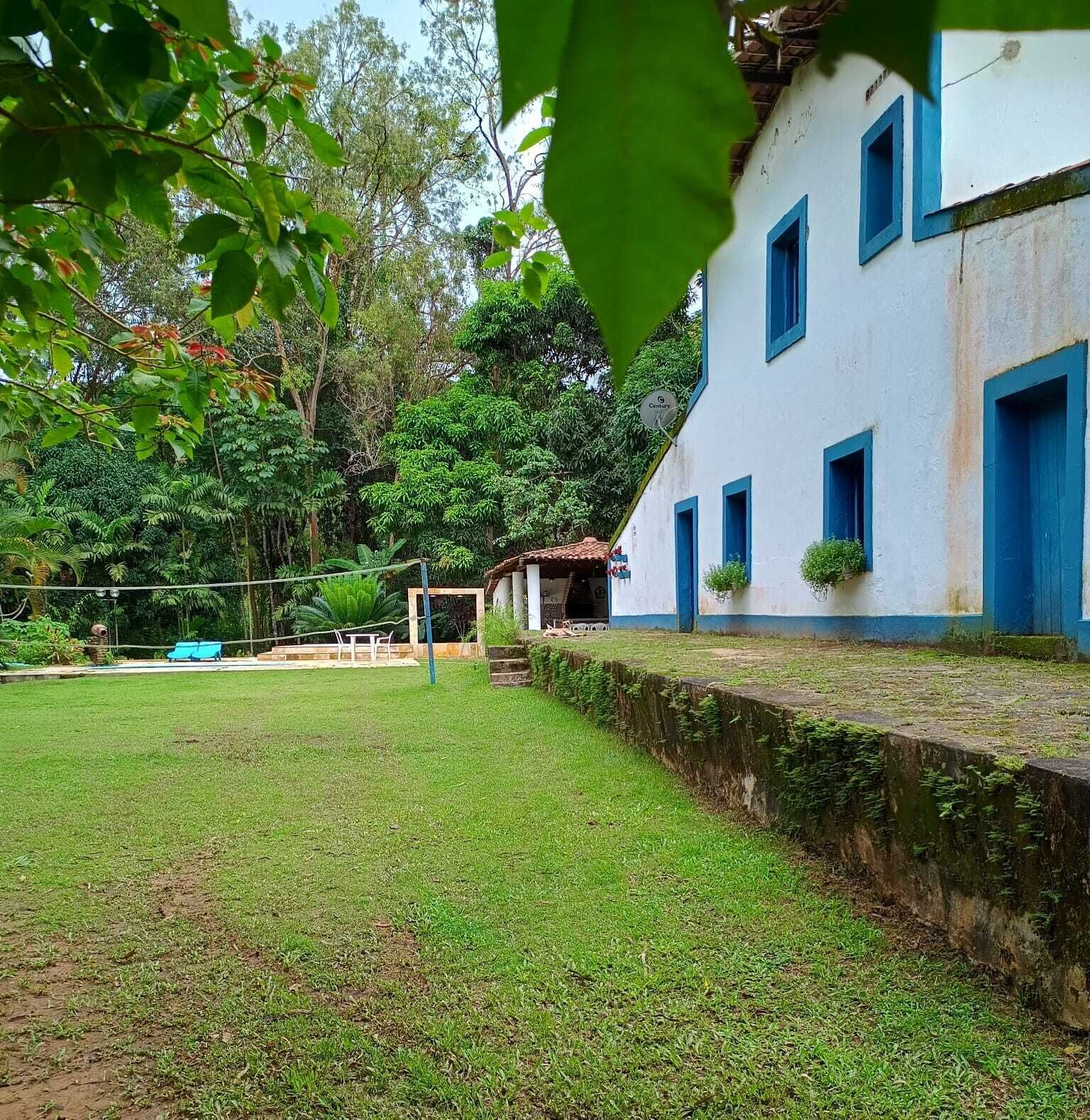 A building with a white exterior and blue trim, surrounded by lush greenery and a well-maintained lawn.