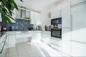 Enjoy cooking in this well-equipped kitchen with white cabinetry, granite countertop, and stainless steel appliances.