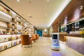 A modern interior with a reception area, a self-service kiosk, and a bookshelf filled with books.
