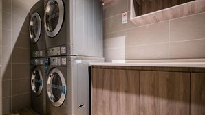 A laundry area with stacked washing machines and a wooden panel wall. - HanTing Hotel (Yan'an University Yangjialing) (Yan'an)
