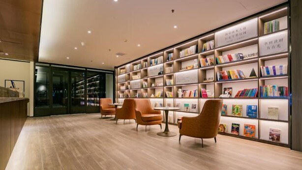 A modern library with bookshelves, comfortable seating, and a wooden floor. - HanTing Hotel (Yan'an University Yangjialing) (Yan'an)