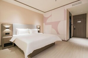 Een moderne hotelkamer met een groot bed, een nachtkastje met een lamp en een houten deur.