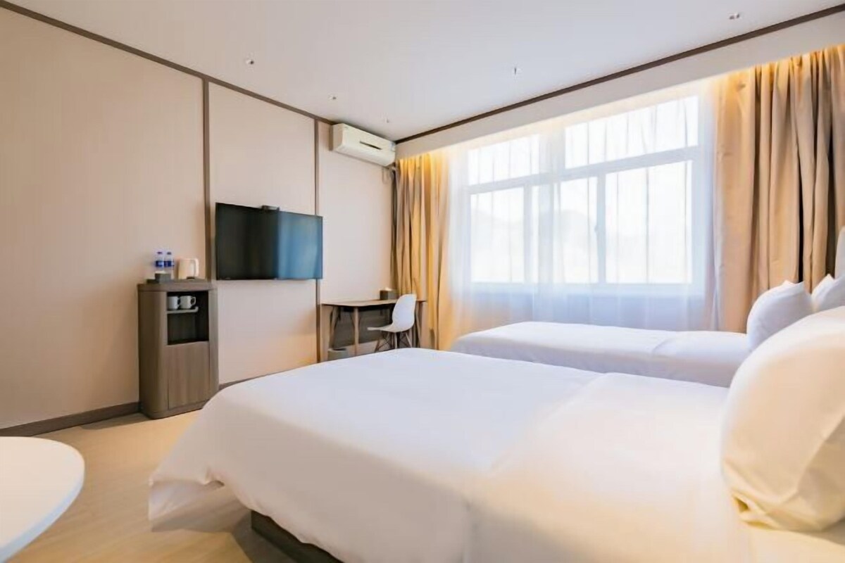 Een hotelkamer met twee bedden, een bureau, een televisie en een minibar.