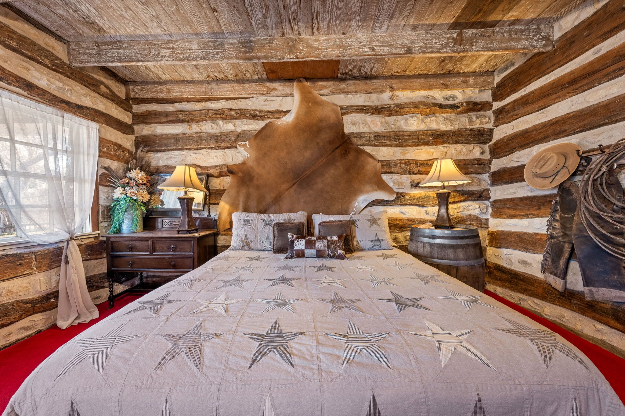 Habitación de cabaña de troncos con un tapete de piel grande, muebles de madera y una pared de piedra.