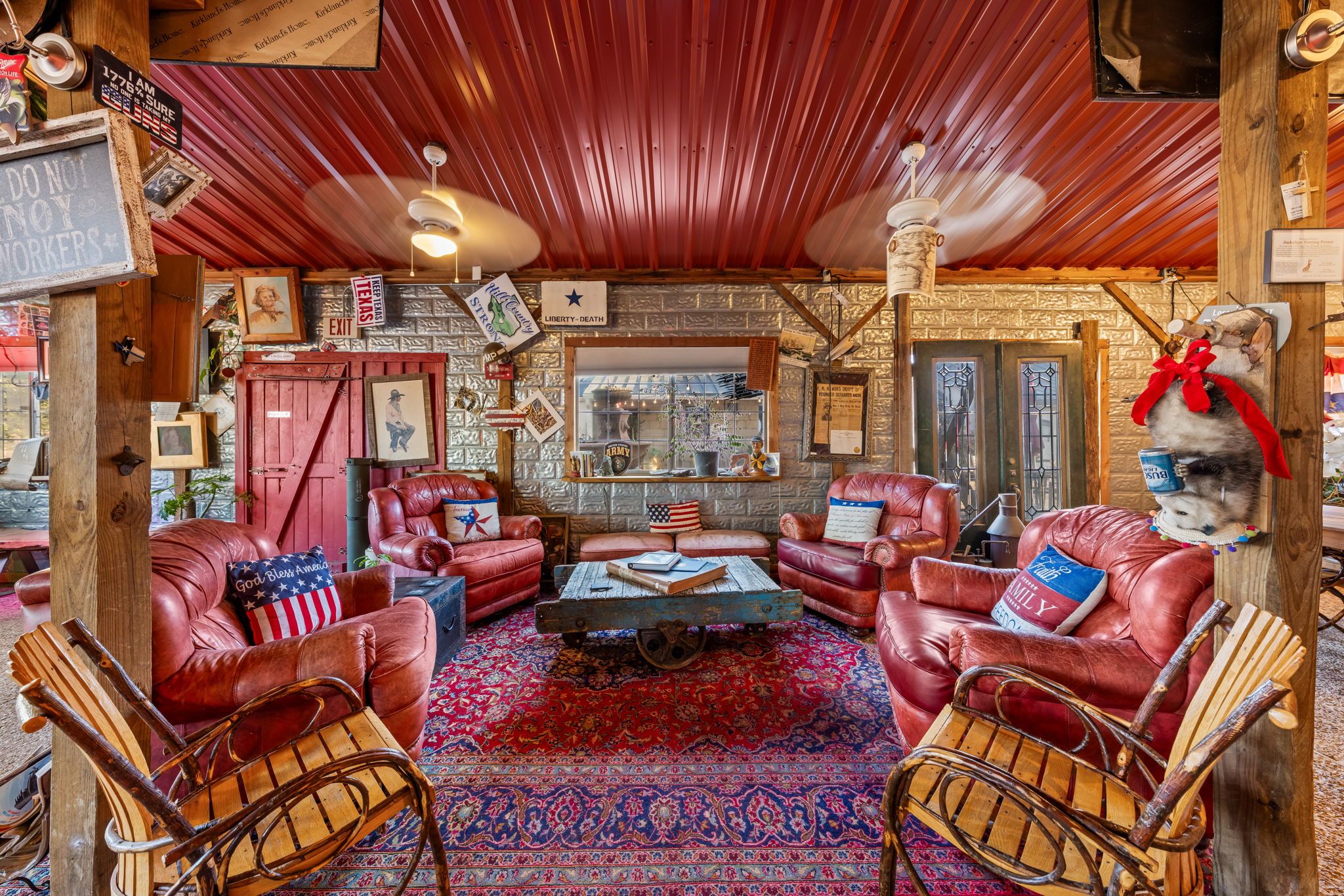A rustic interior with leather sofas, a wooden cart, and a red patterned rug.