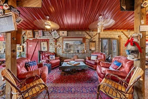 A rustic interior with leather sofas, a wooden cart, and a red patterned rug.