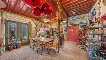 A rustic interior with a wooden table and chairs, a red door, and various decorative items.