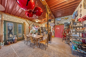 A rustic interior with a wooden table and chairs, a red door, and various decorative items.