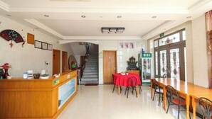 A hotel lobby with a reception desk, a staircase, a dining area with a red tablecloth, and a large window. - Shengsi Jun from the Inn (Shengsi)