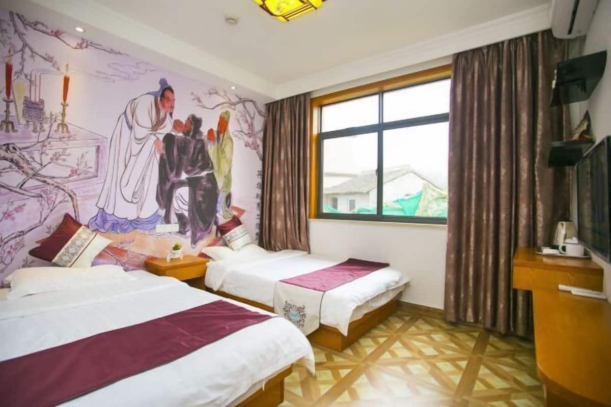 A hotel room with two beds, a large window, a mural on the wall, and a television on a stand.