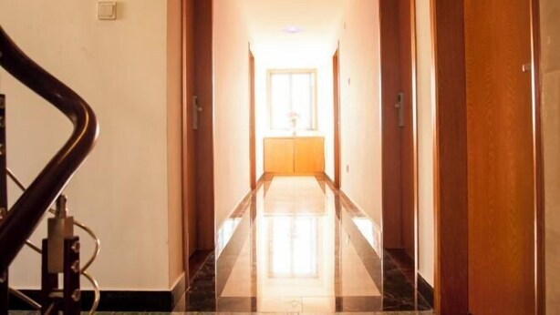 A hotel hallway with a marble floor, wooden doors, and a view into a room at the end. - Shengsi Jun from the Inn (Shengsi)
