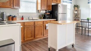 A modern kitchen with wooden cabinets, a white island, and a black refrigerator.