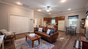 A spacious living room with a brown leather sofa, a wooden coffee table, and a ceiling fan.