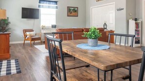 A dining area with a wooden table, black chairs, and a potted plant.