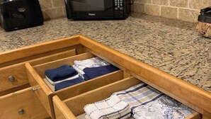 A kitchen with a granite countertop, a microwave, and a drawer with folded towels. - The Bluebonnet 2 Bedroom Family House (Waco)
