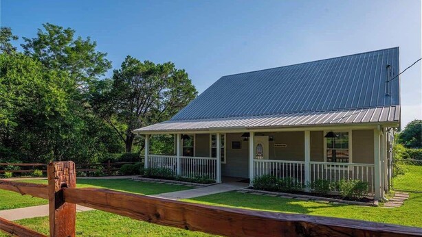 A single-story building with a metal roof and a porch. - The Bluebonnet 2 Bedroom Family House (Waco)