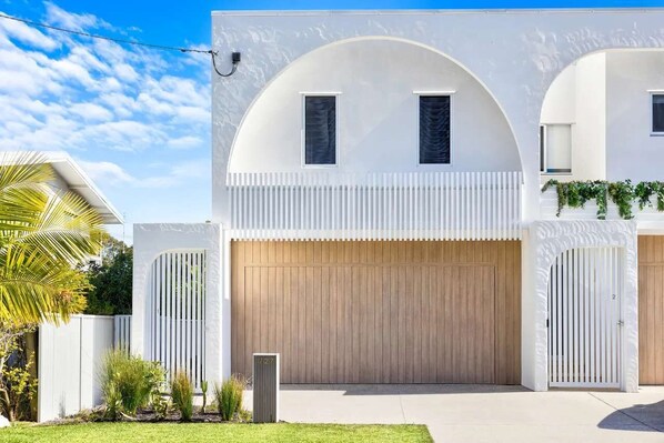 A modern two-story house with a large garage, white exterior walls, and a curved archway. - Key West Beach House (Coolum Beach)