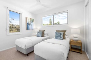 A room with two beds, a ceiling fan, and large windows with a view of trees and sky. - Key West Beach House (Coolum Beach)