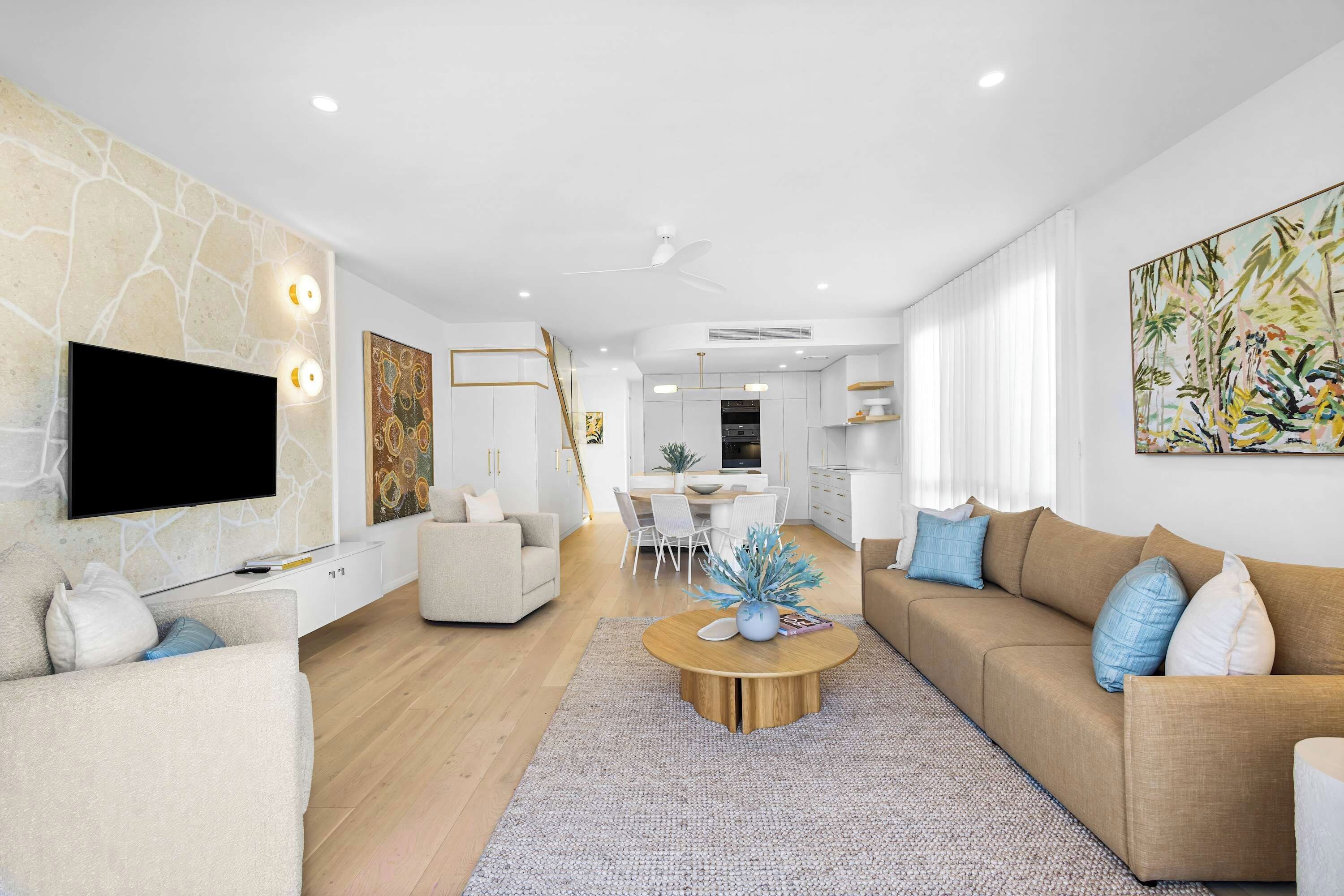 Una sala de estar moderna con un televisor de pantalla plana, un sofá, una mesa de centro y una zona de comedor con una mesa y sillas.