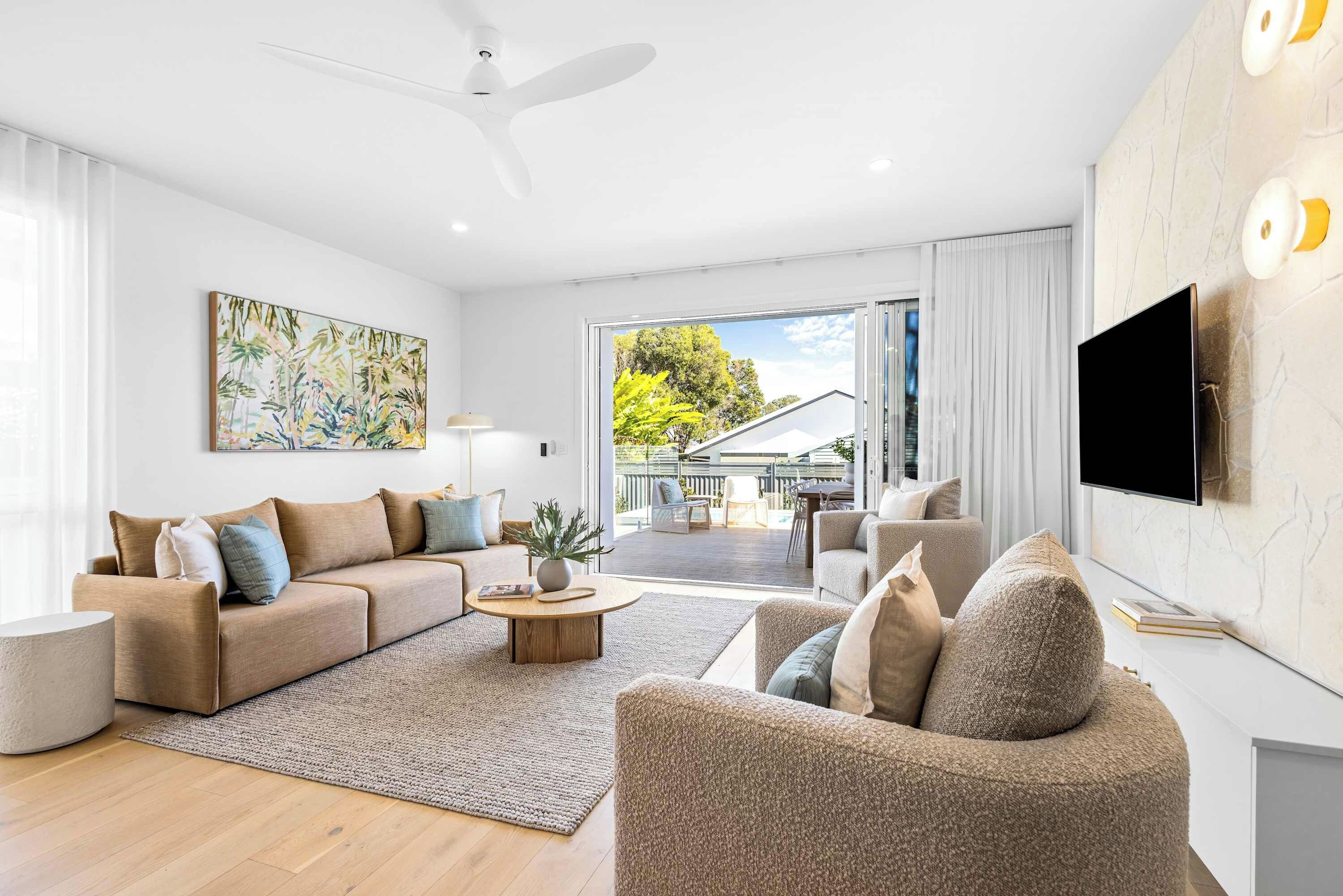 A modern living room with a sofa, armchairs, a coffee table, and a flat-screen TV.