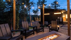 Een terras met houten stoelen en een ingebouwde vuurkuil.