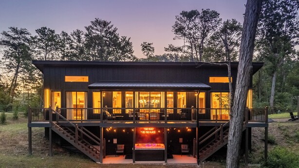 Een moderne cabin met een glazen gevel, een houten terras en een gedeelte met een jacuzzi.
